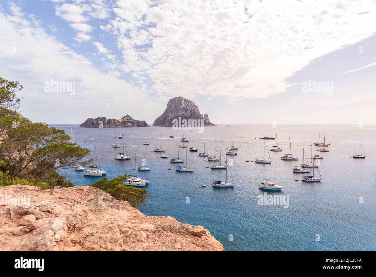 Anchored catamarans and sailing yachts in bay Cola d'Hort against backdrop of two lovely rocky islands Es Vedra and Es Vedranell. Ibiza, Balearic Isla Stock Photo