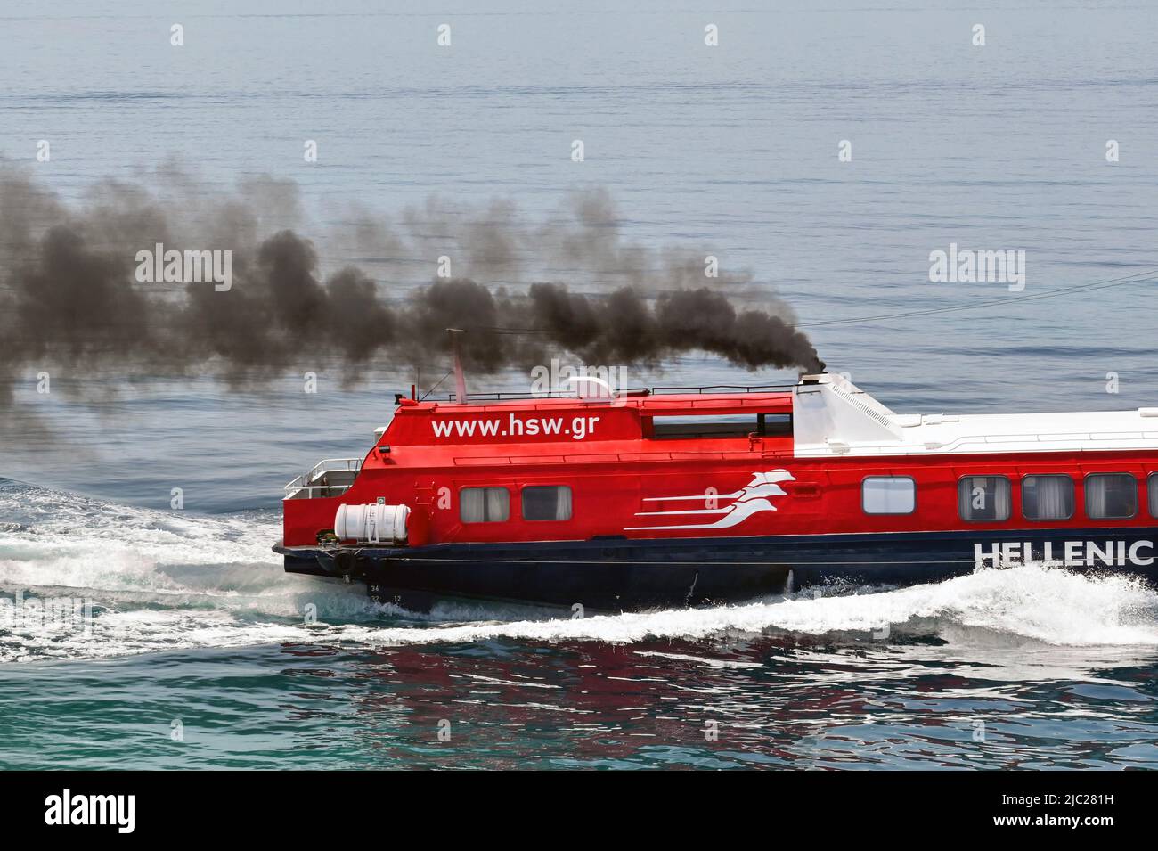 Aegina, Greece, - May 2022: Close up of the rearer of a fast hydrofoil ferry accelerating with thick black smoke emerging from its funnels. Stock Photo