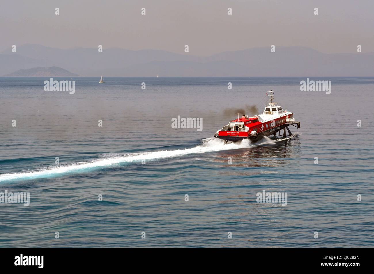 Aegina, Greece, - May 2022: Fast hydrofoil ferry accelerating with thick black smoke emerging from its funnels. Stock Photo