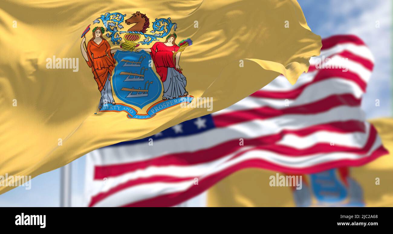 The New Jersey state flag waving along with the national flag of the United States of America. In the background there is a clear sky. New Jersey s a Stock Photo