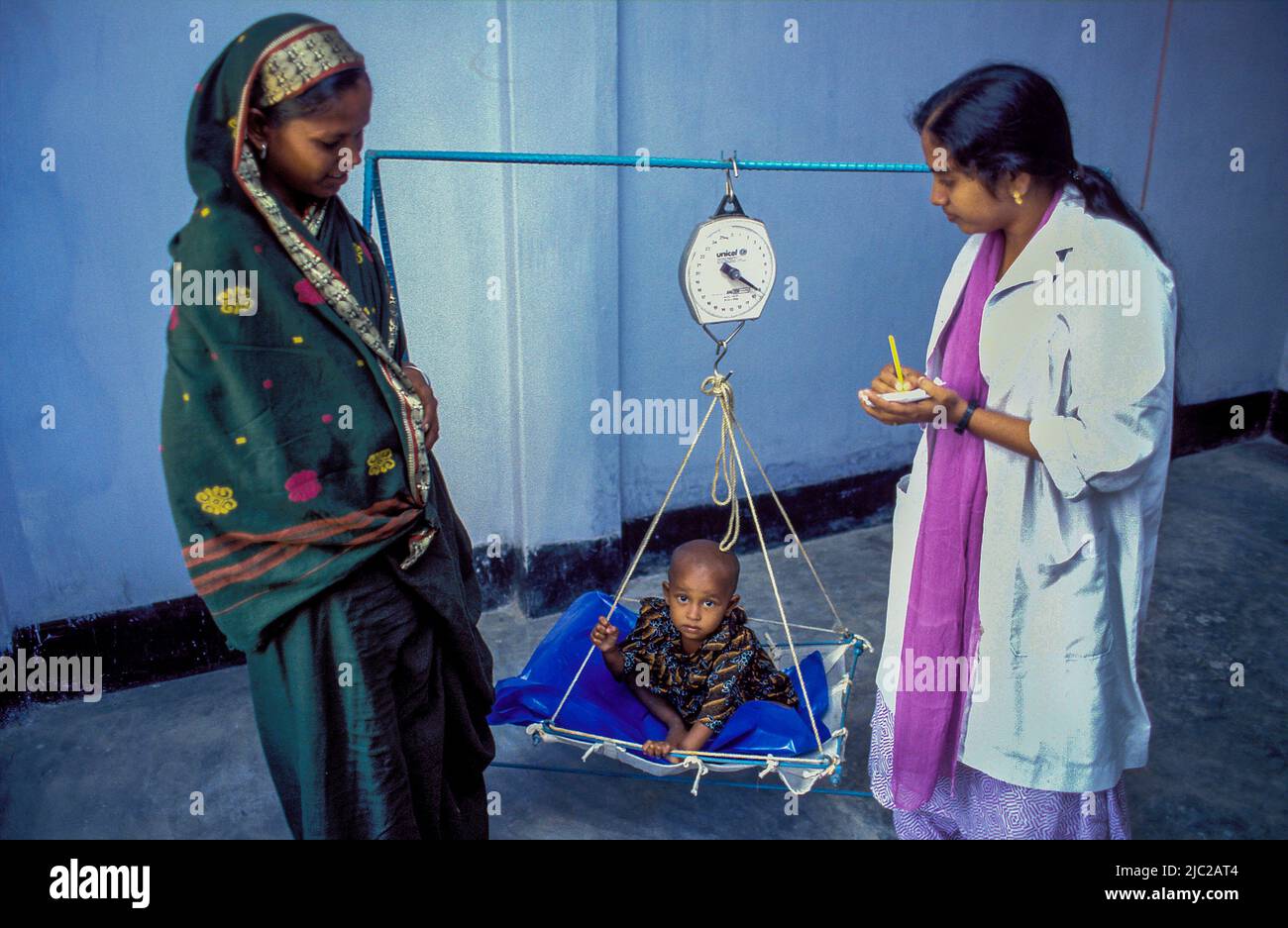 Bangladesh; young child is weighed on a scale at a public health clinic. Stock Photo