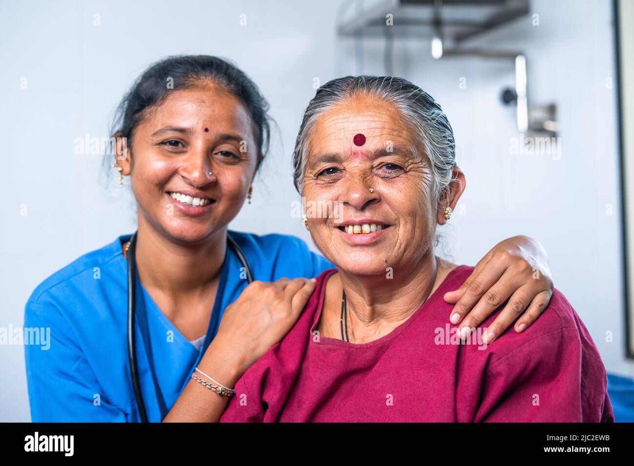 Happy smiling nurse hugging or embracing senior sick women by looking camera at hospital bed - concept of medicare, healthcare treatment and friendly Stock Photo
