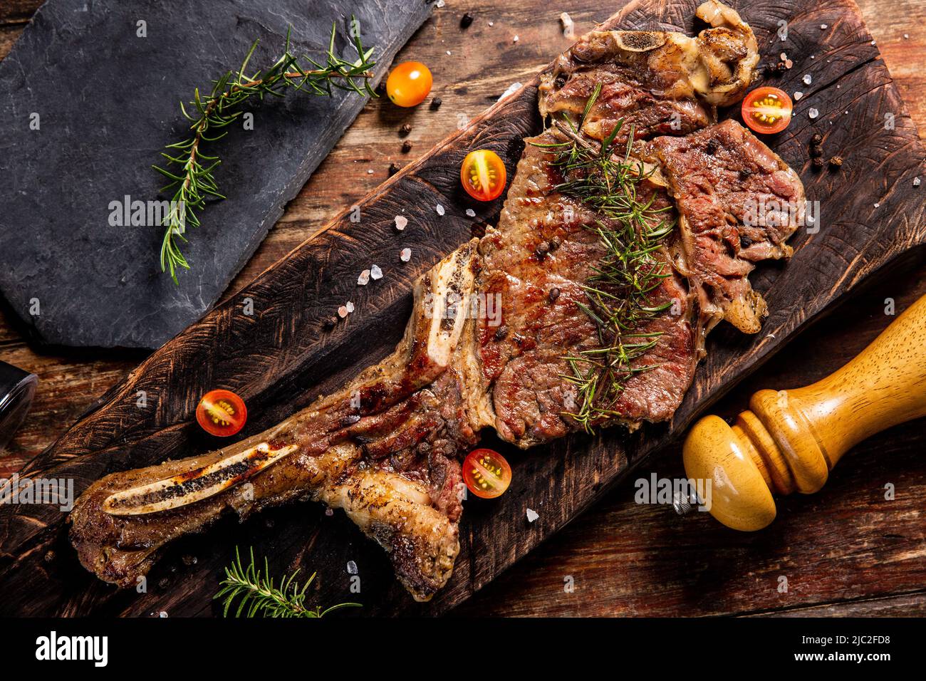 Tomahawk steak  on wooden with salt and black pepper,Garnish with rosemary.Top view,World food day Stock Photo