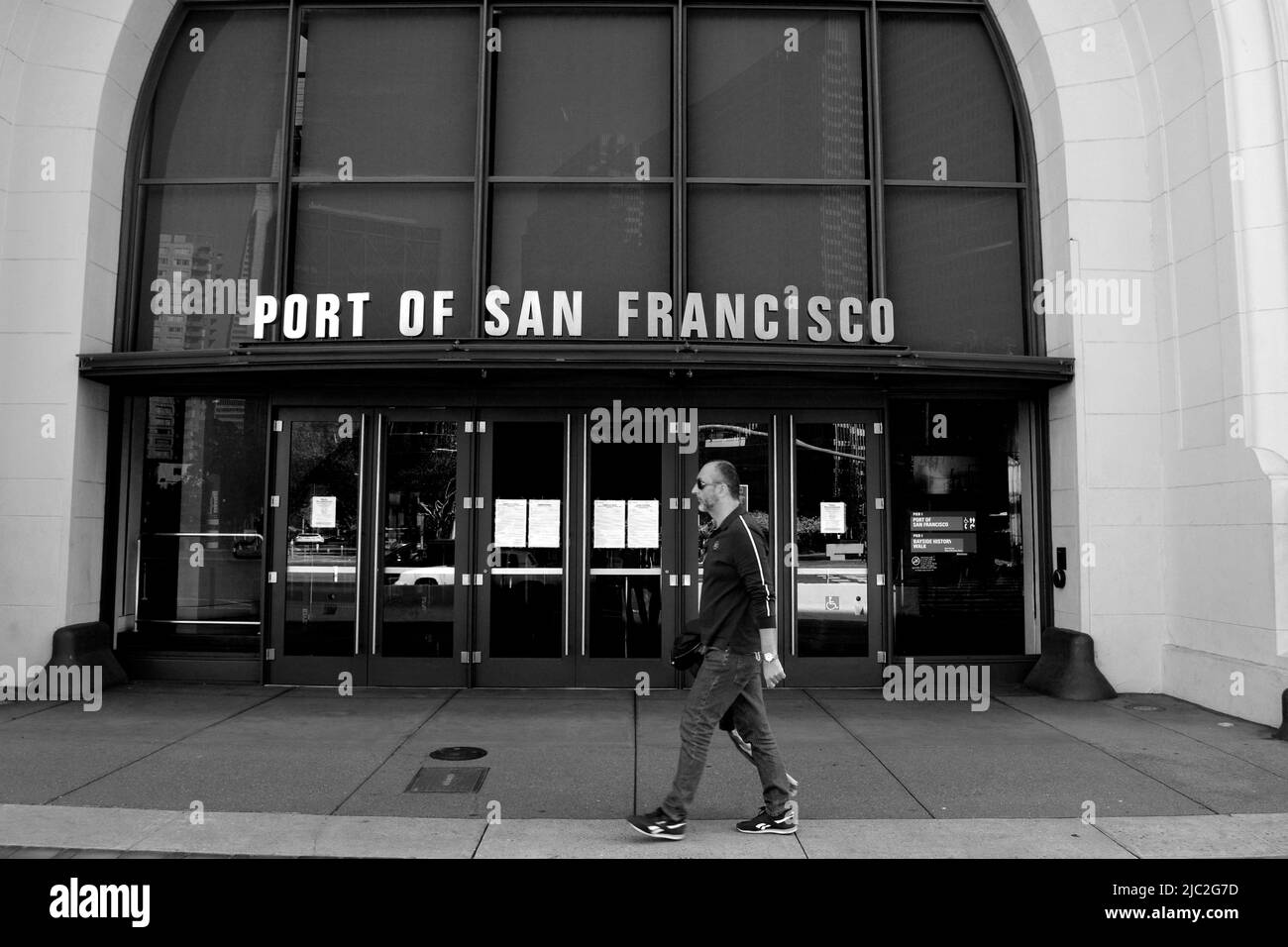 A man walks along The Embarcadero waterfront and its piers in the Port of San Francisco in California. Stock Photo