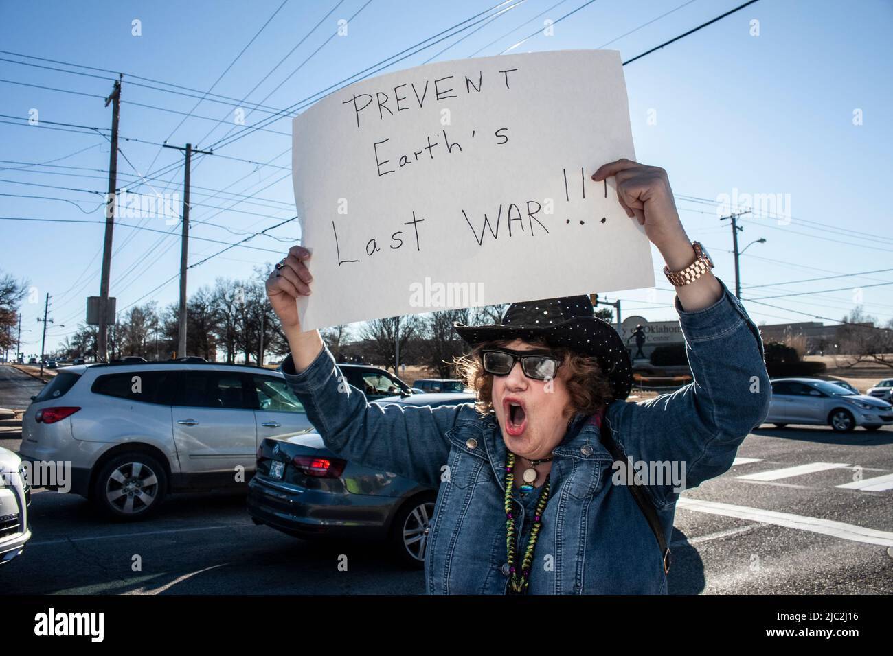 01-04-2020 Older woman in cowboy hat and much jewelry chants as she holds up sign Prevent Earths Last War Stock Photo