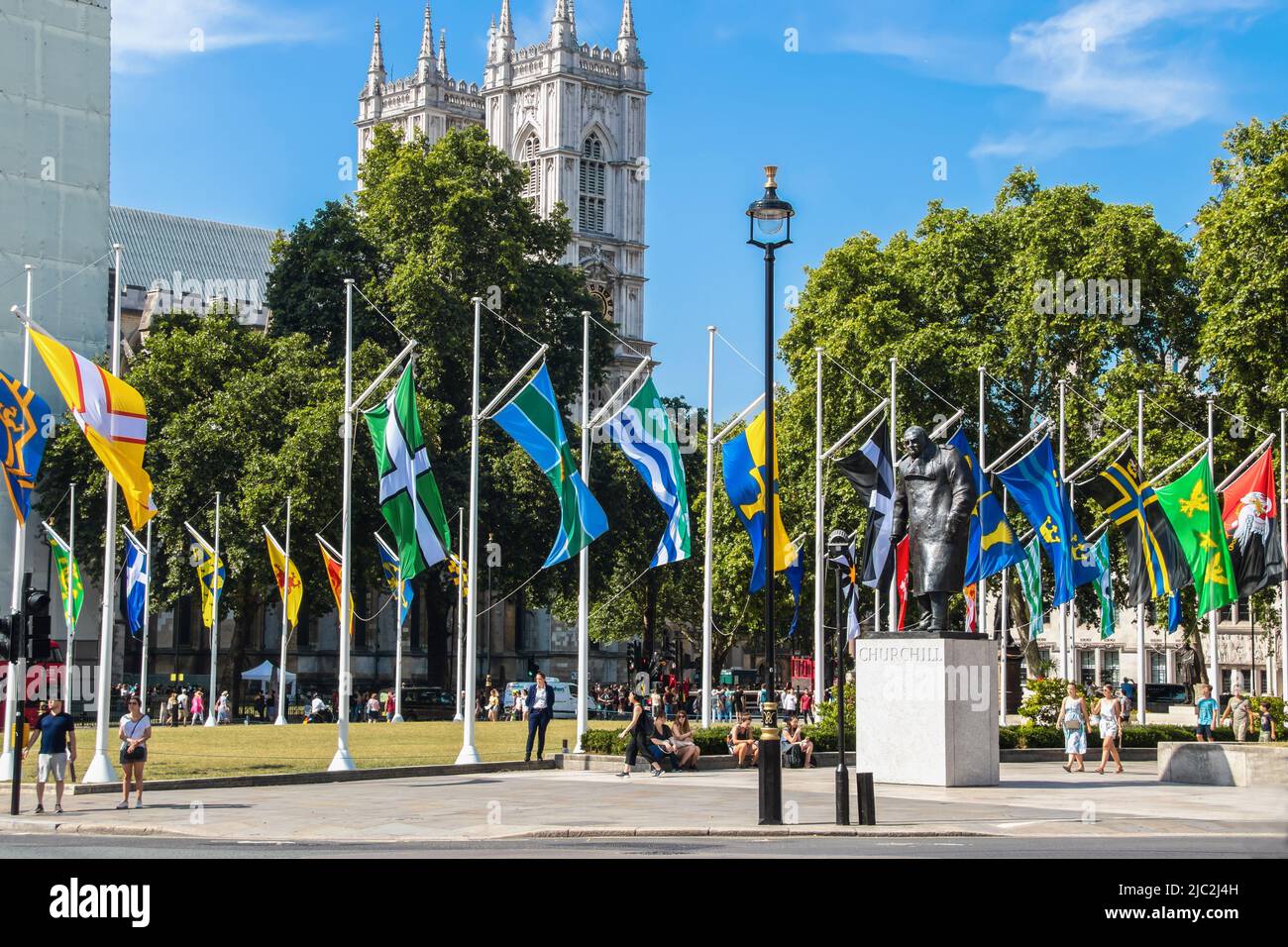 7-24-2019 London UK - Statue of Winston Churchill in Parliament Square with the flags of the Crown Dependencies and Overseas Territories flying on sun Stock Photo