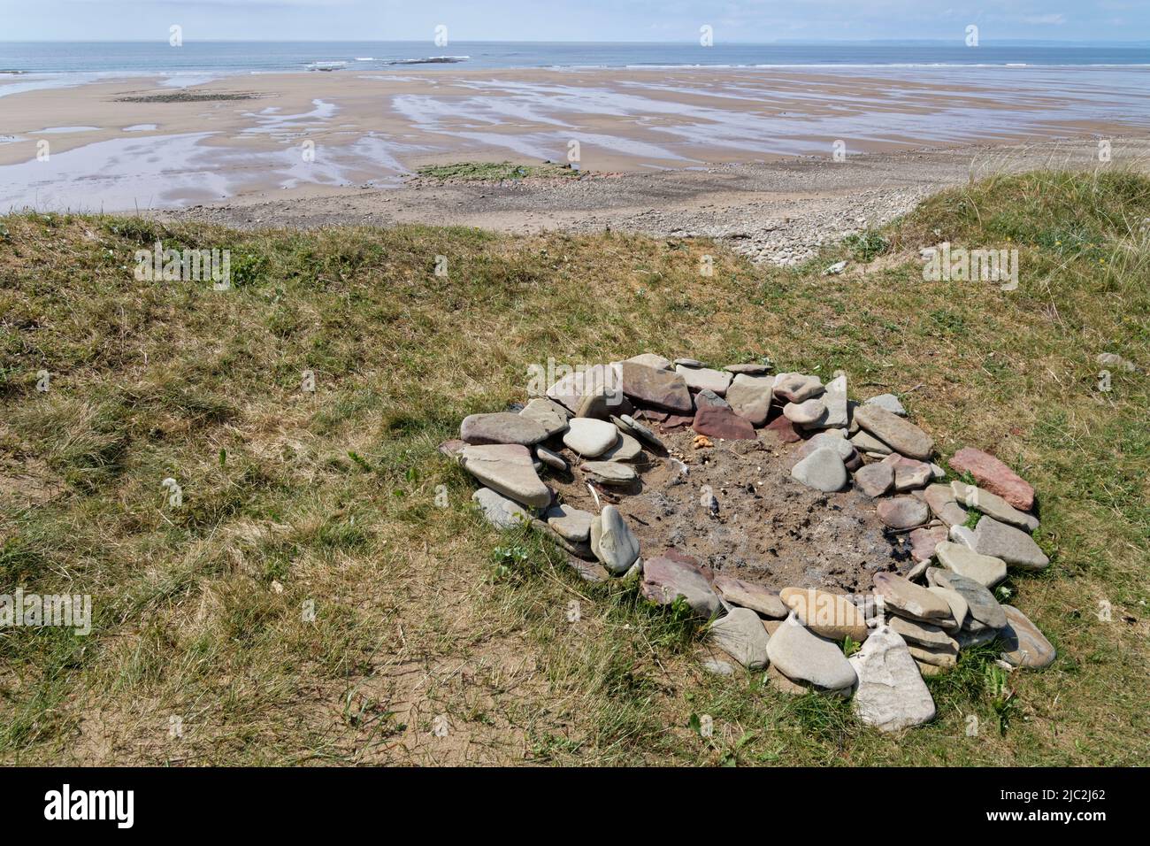 Remains of a camp fire on coastal sand dunes on the sea front, likely to cause damage to vegetation and worsen coastal erosion, Kenfig NNR, Wales. Stock Photo