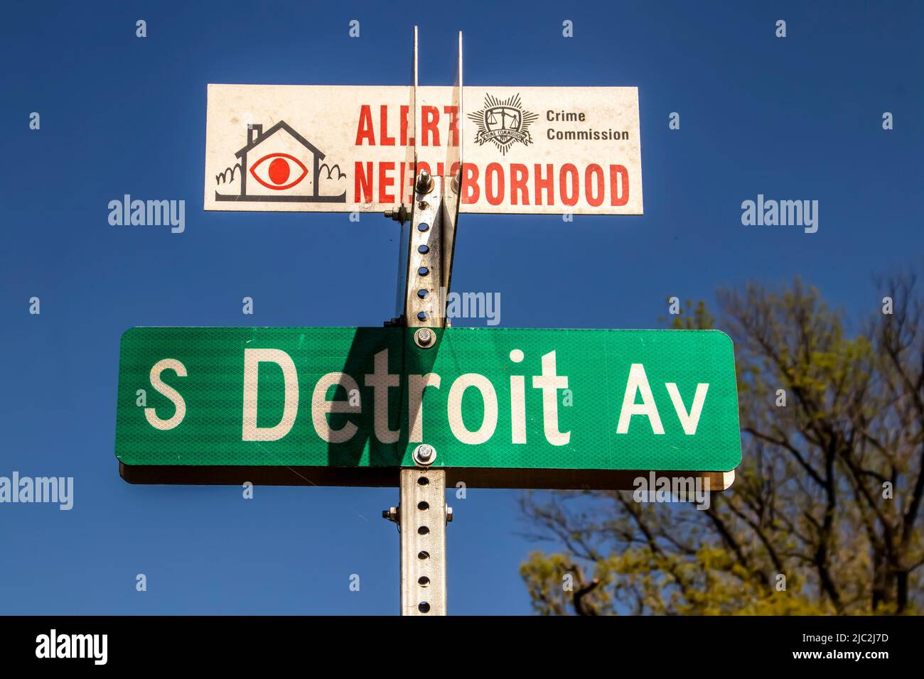 2022 04 26 Tulsa OK USA Alert Neighborhood Crime Commission sign on top of S Detroit Ave street sign bolted onto metal pole with deep blue sky and blu Stock Photo