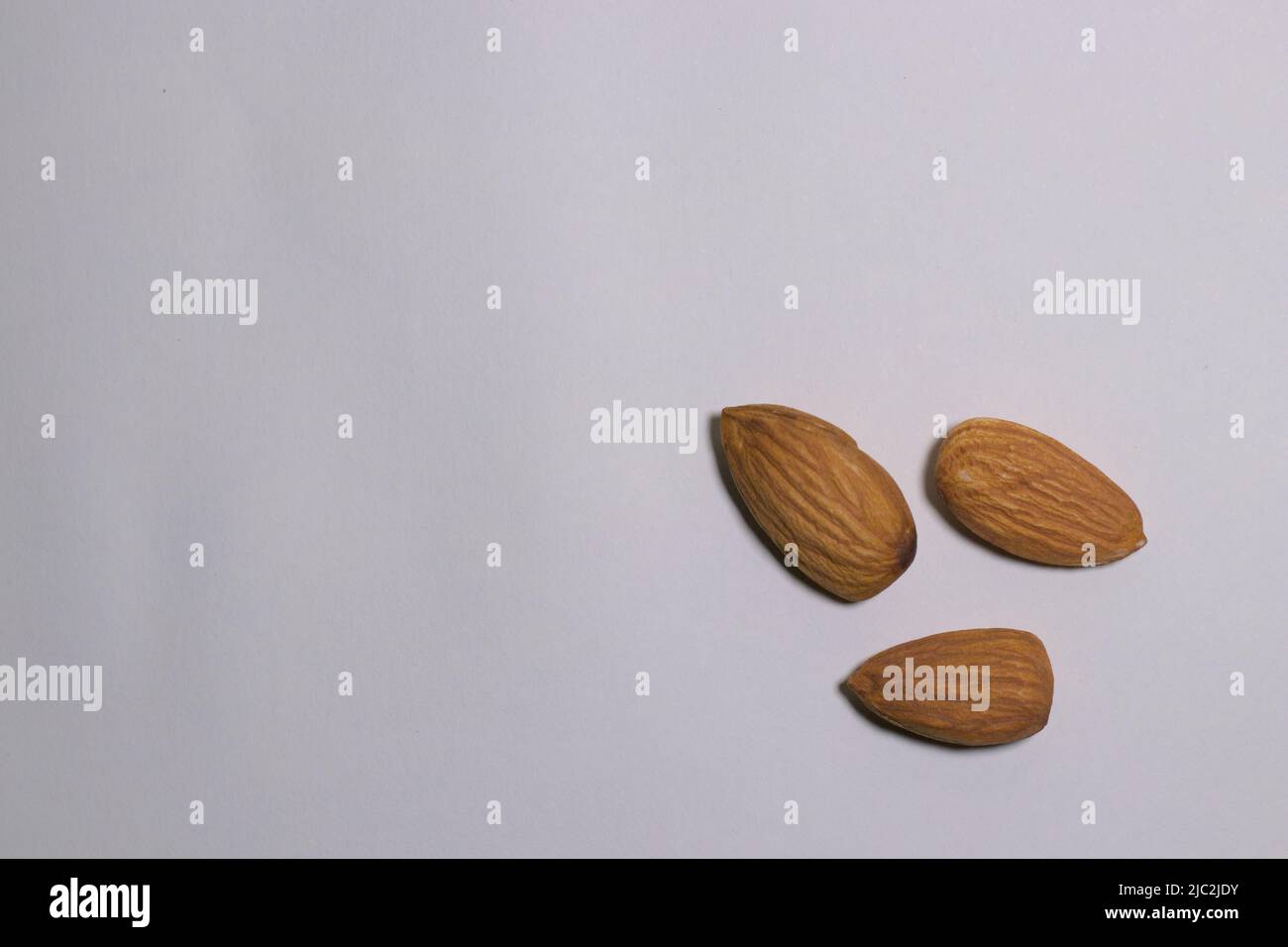 3 Almonds on a white surface, top view, text space. Stock Photo