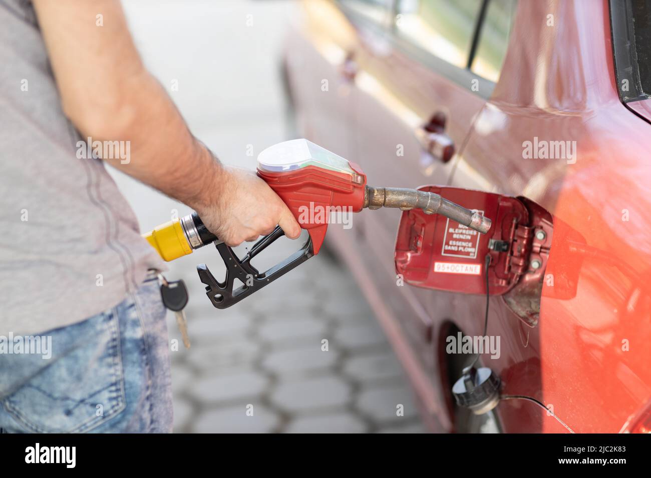 Man filling fuel tank in his hand at gas station. Price inflation sanctions Stock Photo