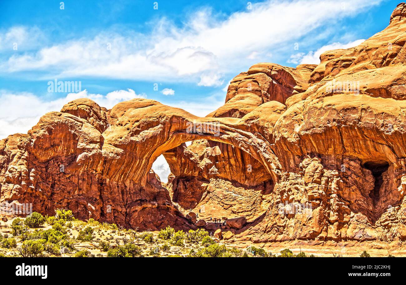 Famous Double Arches aka The Spectacles in Arches National Park in Utah USA with tiny ant-sized tourists exploring inside Stock Photo