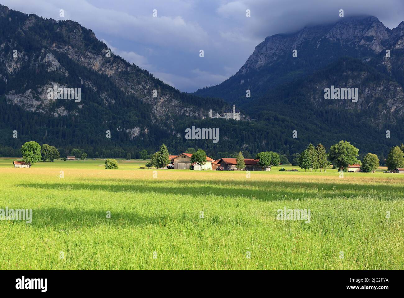 Sunshine on the meadow, dark clouds in the mountains Stock Photo