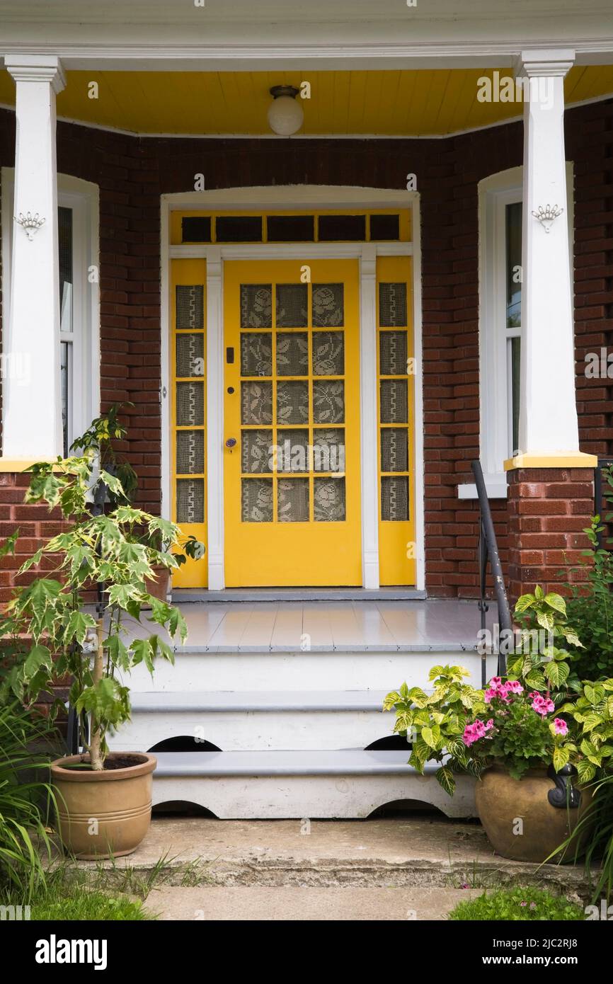 Old 1927 red brick home with yellow entrance door and grey wood plank