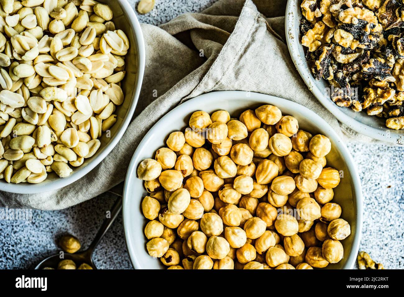 Overhead view of three bowls of hazelnuts, walnuts and peanuts Stock Photo
