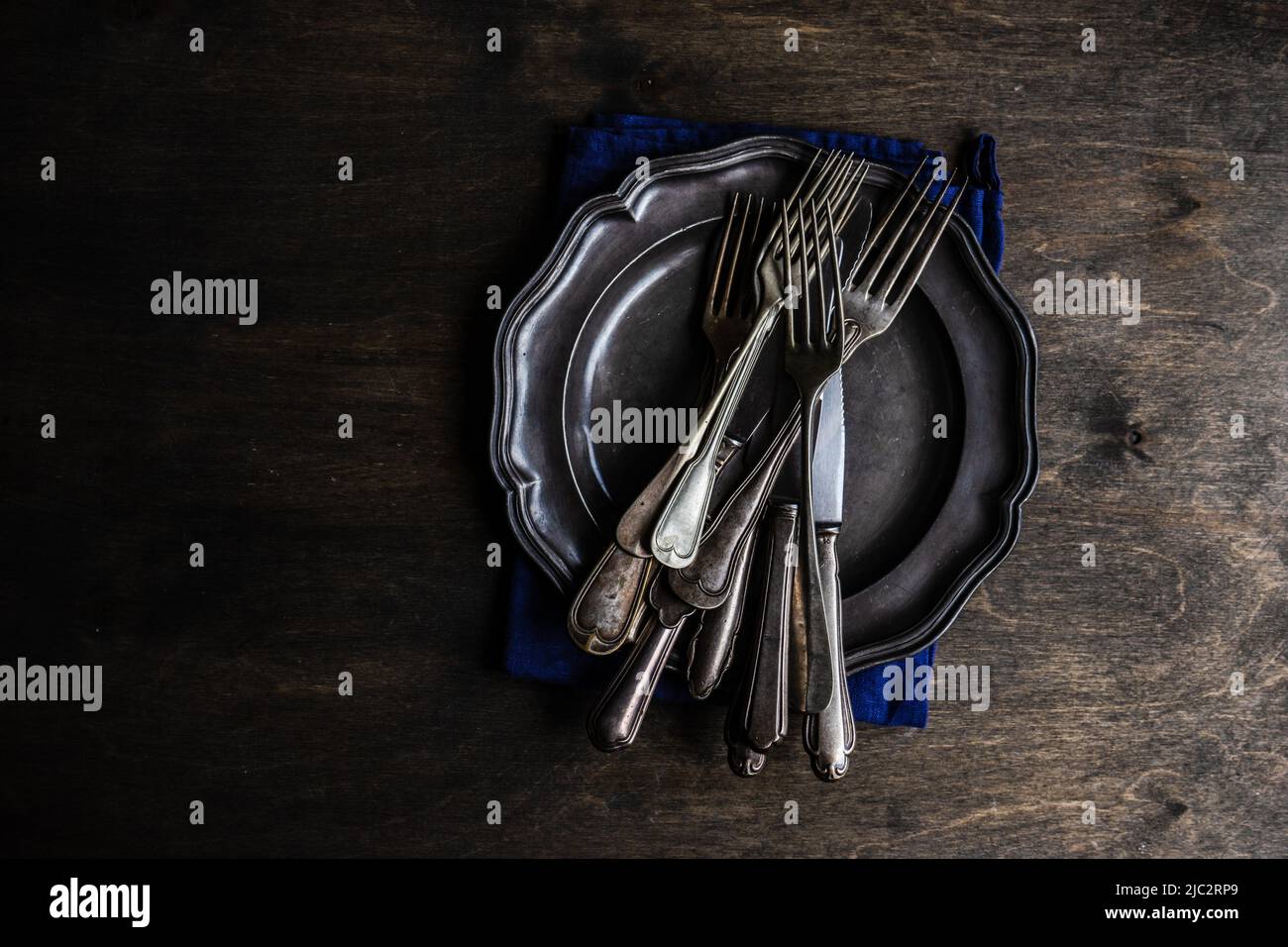 Overhead view of vintage knives and forks on a pewter plate Stock Photo