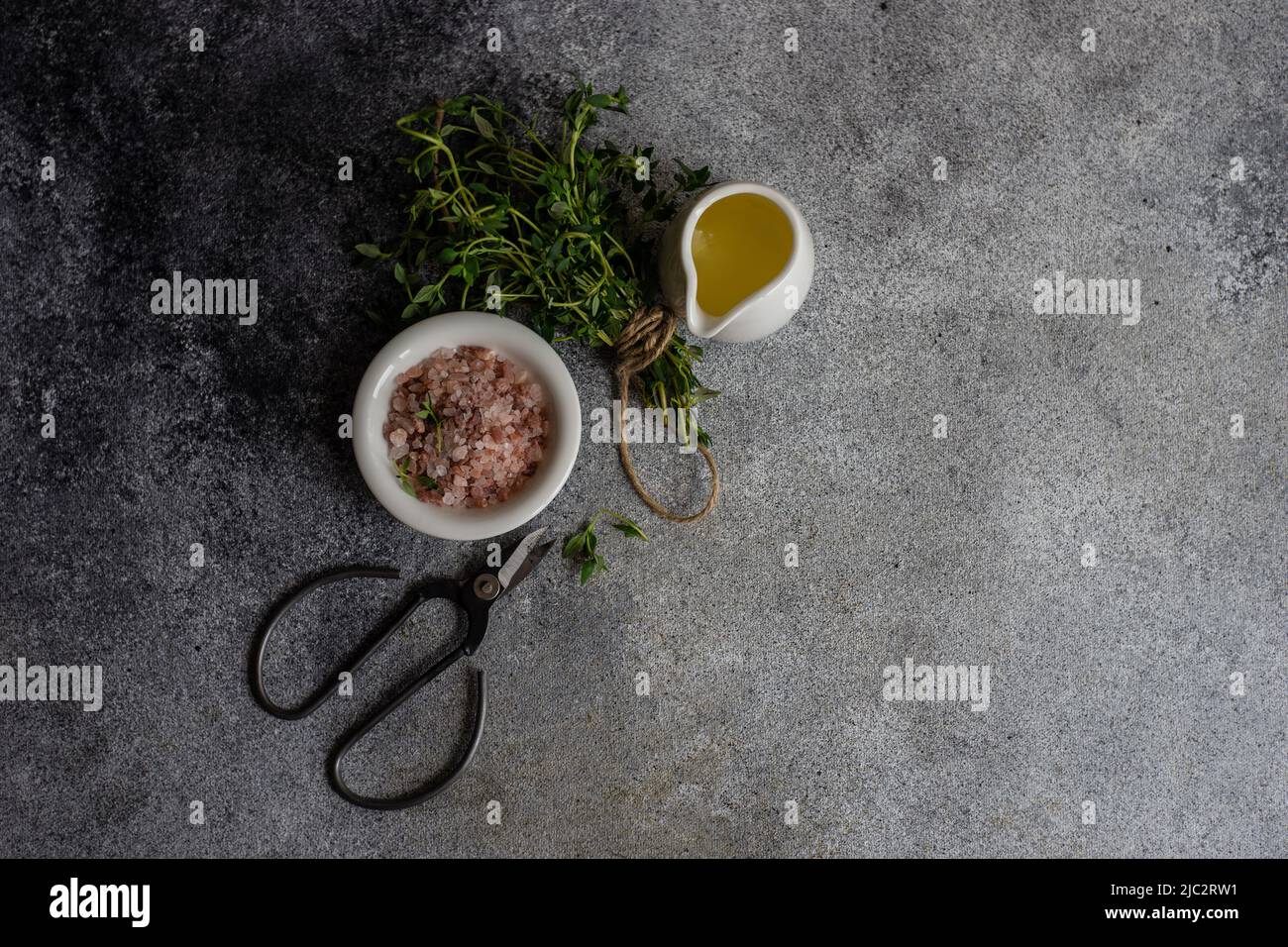 Overhead view of a bunch of fresh thyme, olive oil, pink Himalayan salt  and scissors Stock Photo