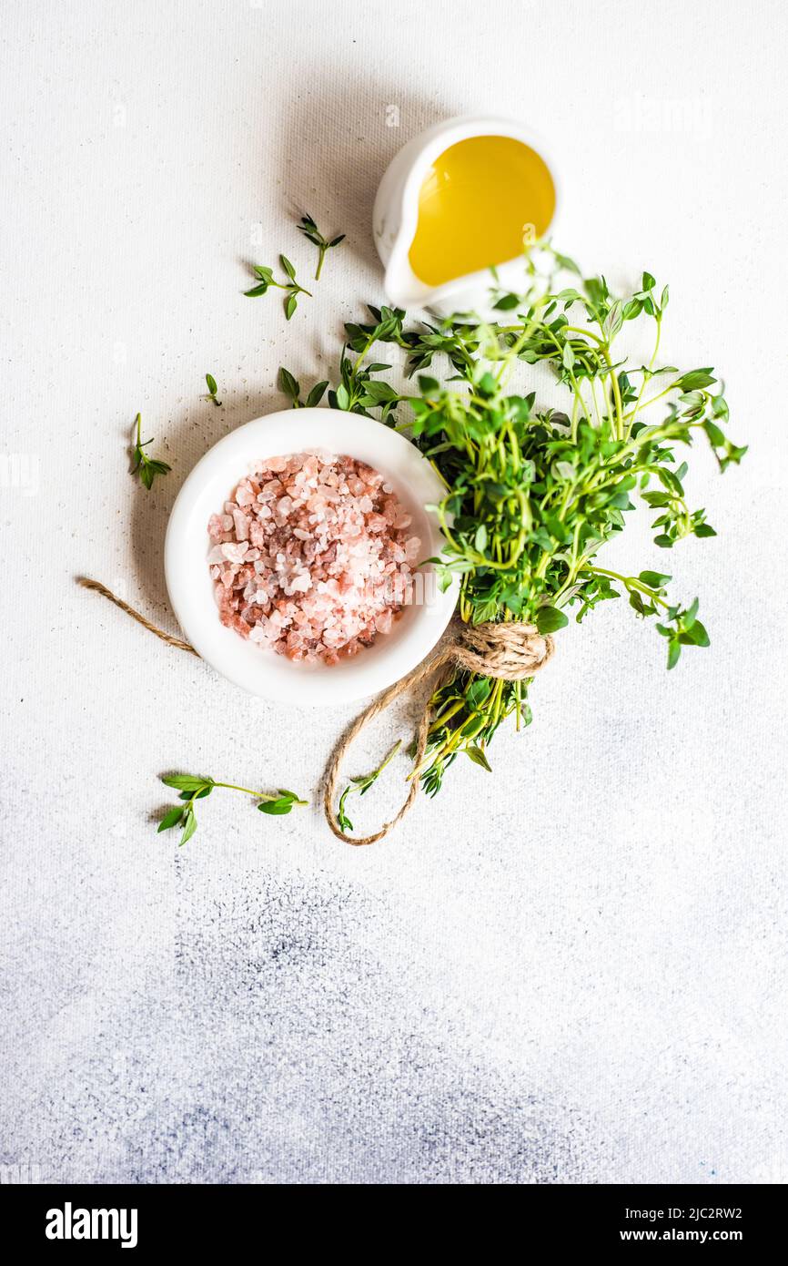 Overhead view of a bunch of fresh thyme next to a pot of pink Himalayan salt and a jug of olive oil Stock Photo
