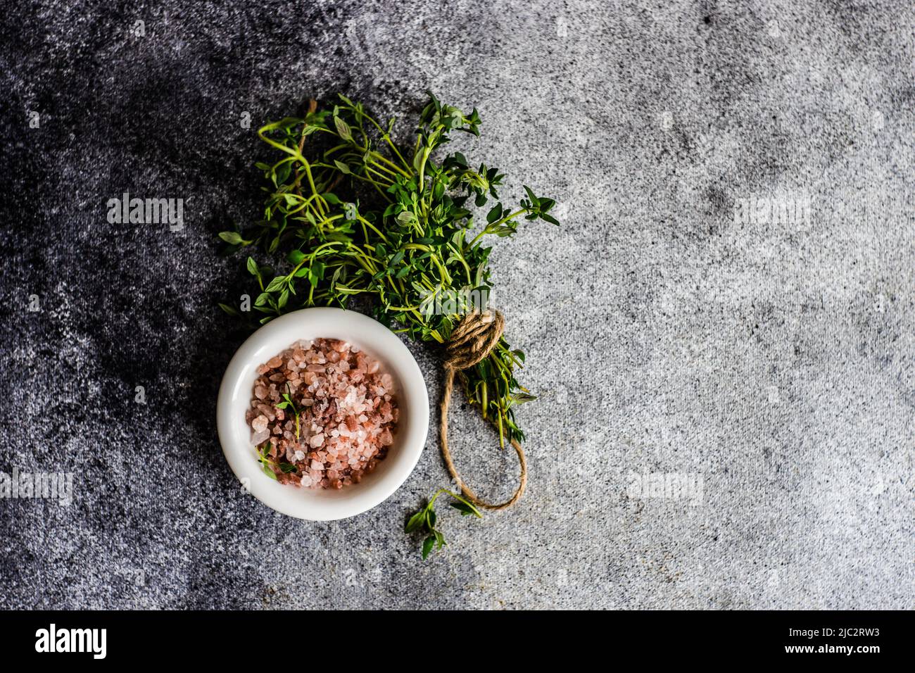 Overhead view of a bunch of fresh thyme next to a pot of pink Himalayan salt Stock Photo