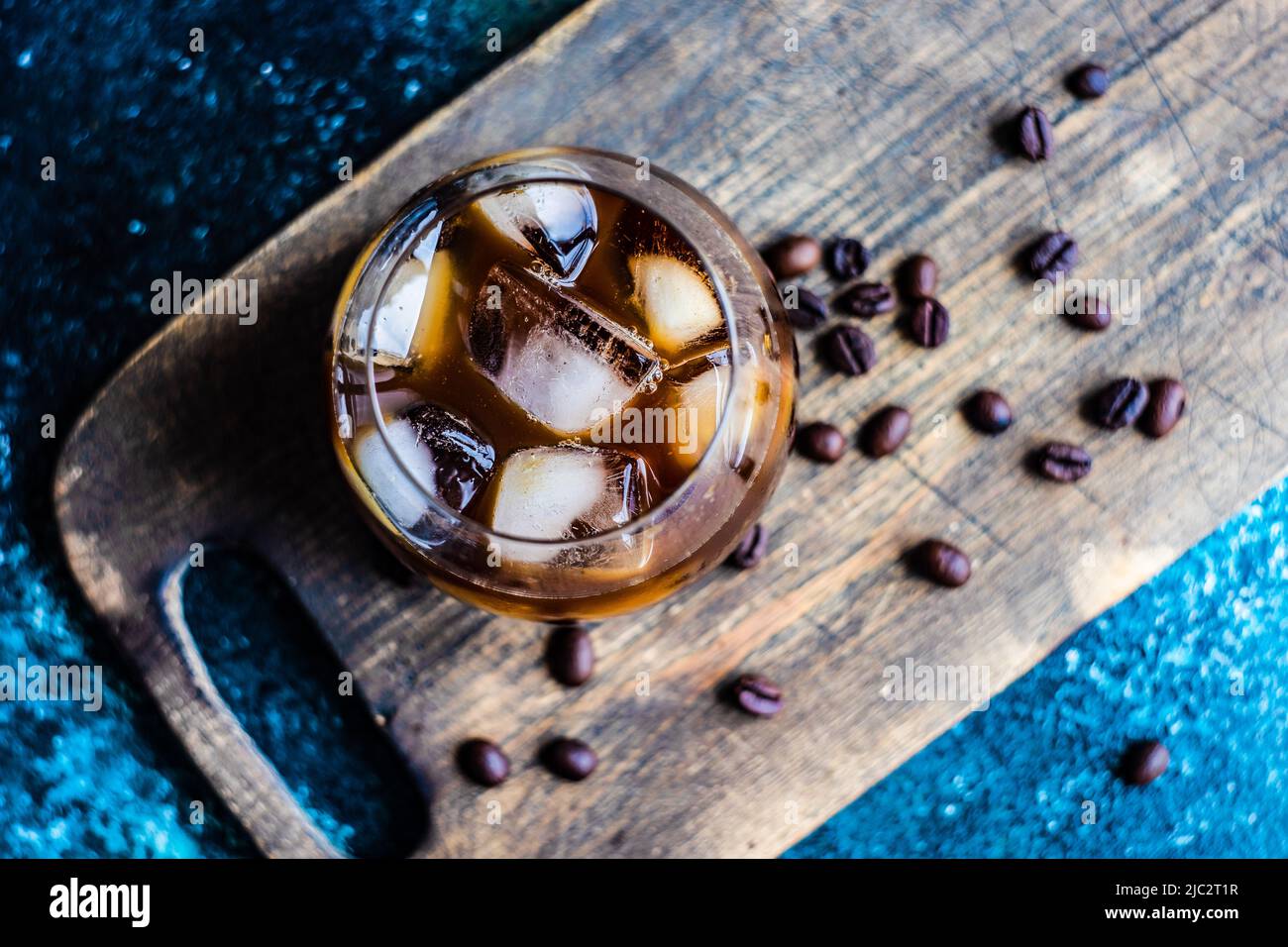 Close-up of an iced coffee drink on a chopping board with roasted coffee beans Stock Photo