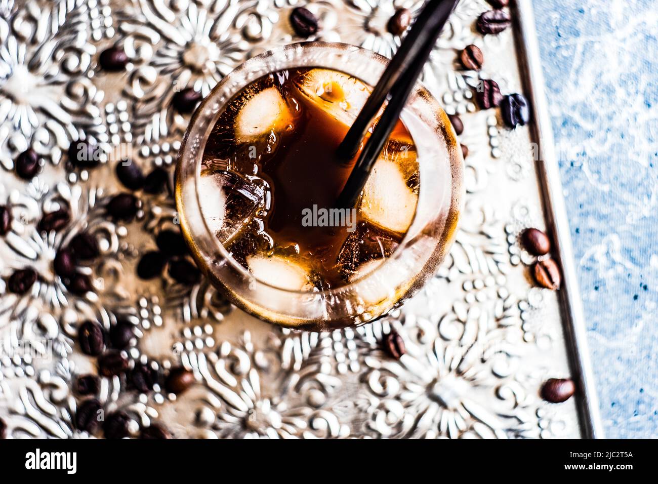 Close-up of an iced coffee drink on metal tray with roasted coffee beans Stock Photo