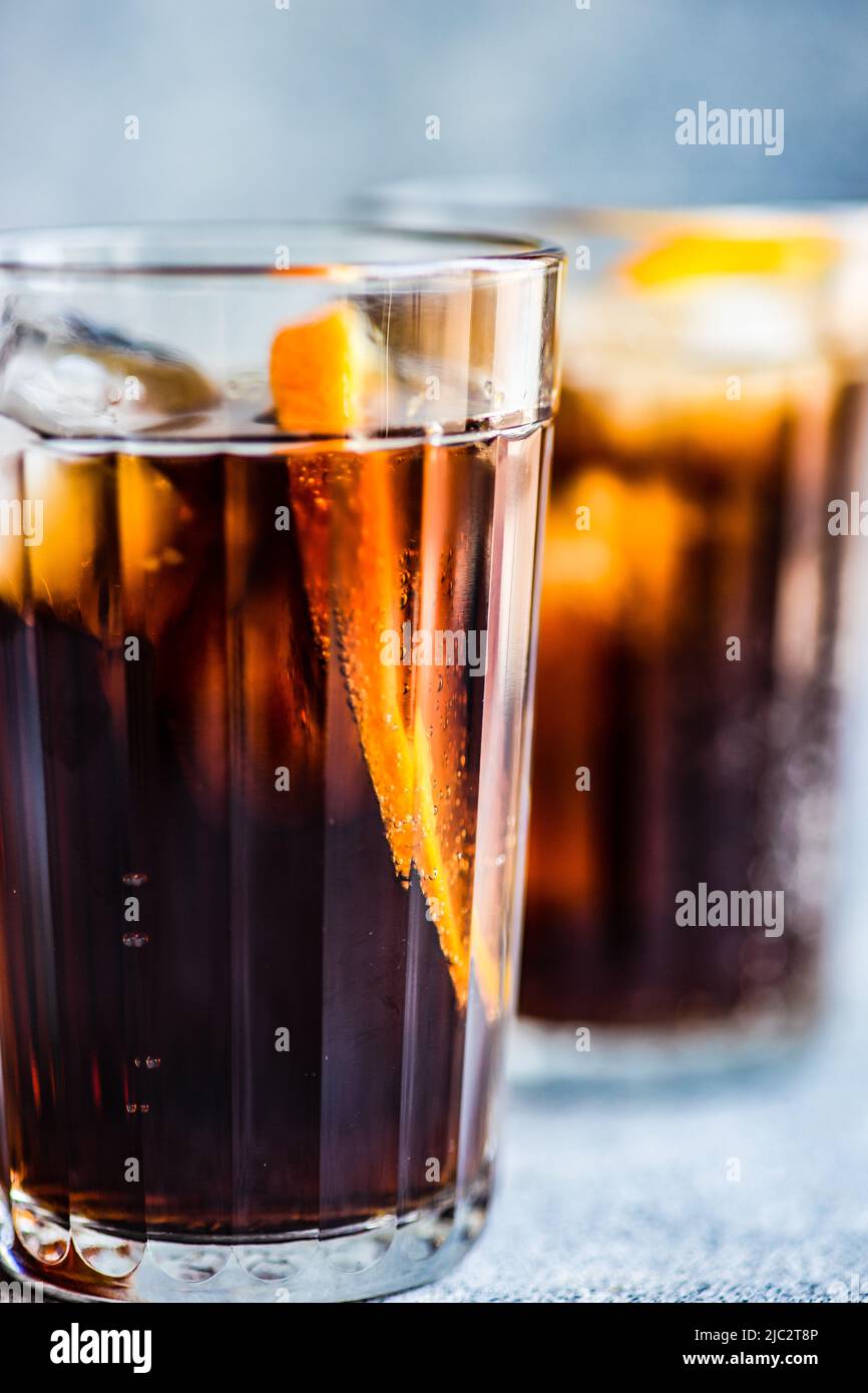 Close-Up of two cola drinks with ice cubes and a slice of orange Stock Photo
