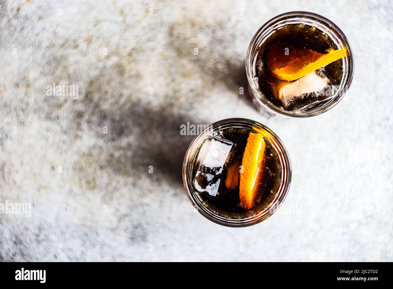 Overhead view of two cola drinks with ice cubes and slices of fresh orange Stock Photo