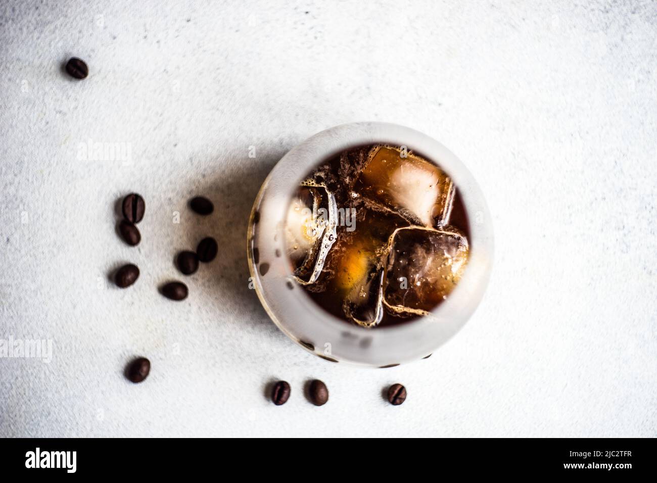 Overhead view of an iced coffee drink on a table with roasted coffee beans Stock Photo