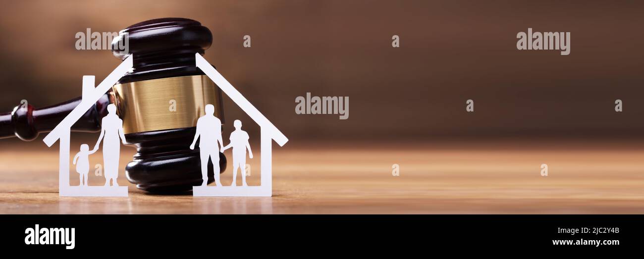 White Family Paper Cut Out In Front Of Judge Gavel On The Wooden Desk Stock Photo