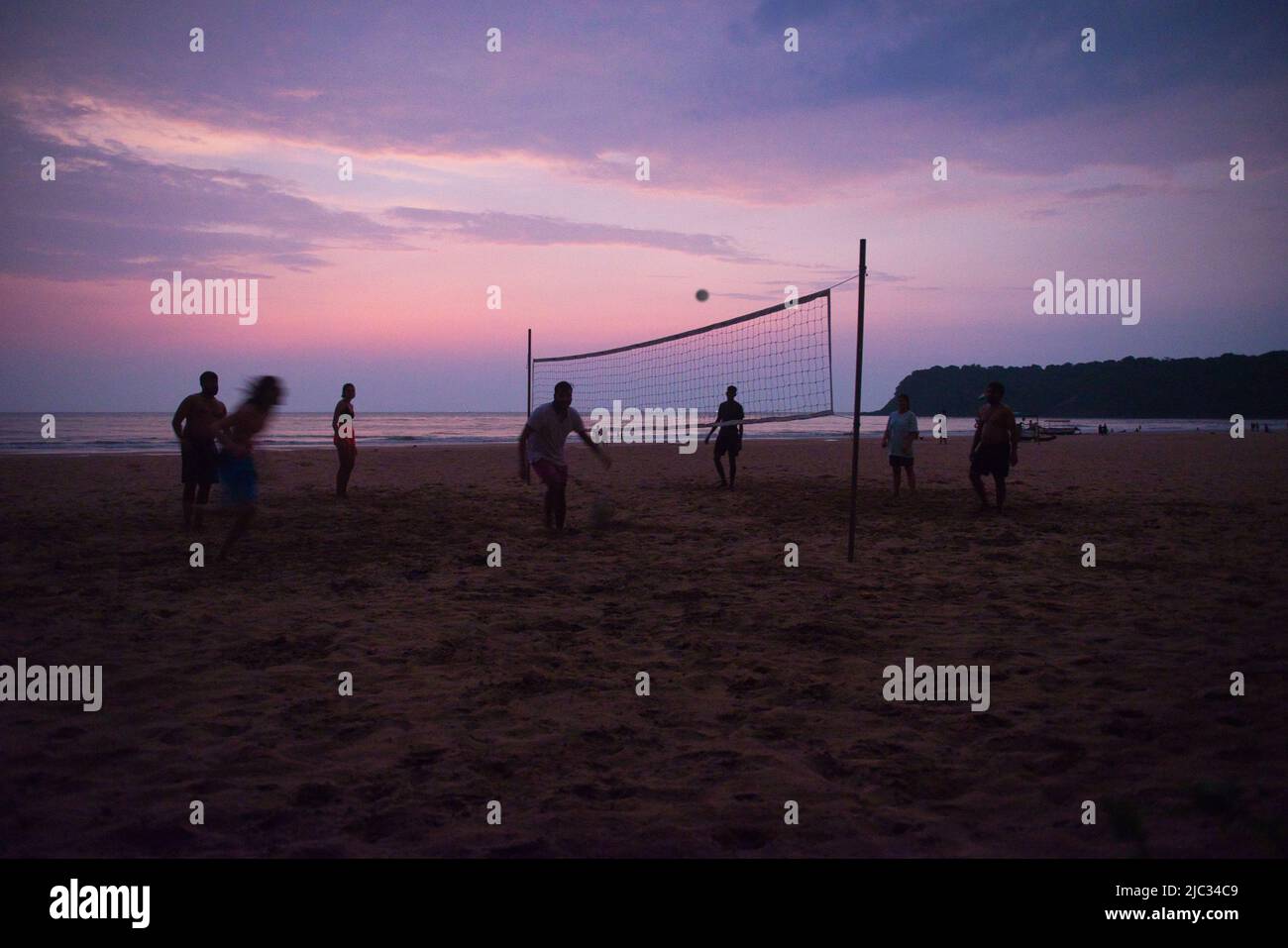 Goa, India - 25 October 2021: Young people playing a friendly game of volleyball on a Goa beach against a beautiful sky Stock Photo