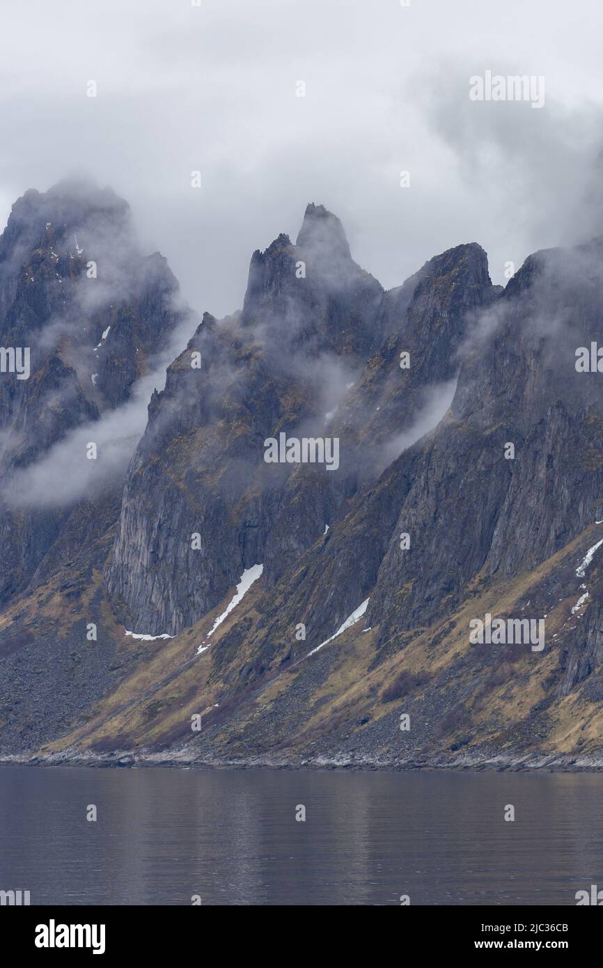 Ramnen, Hundslaupen and Teigen mountains seen from Ersfjordbotn, Senja, Northern Norway. On a foggy day. Stock Photo