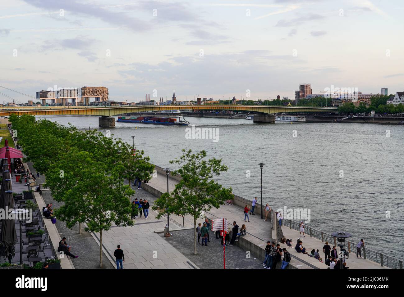 People on the bank promenade of the Rhine. Rheinauhafen with crane ...