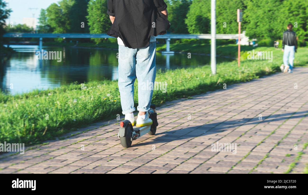 young man on an electric scooter kickscooter at urban promenade Stock Photo