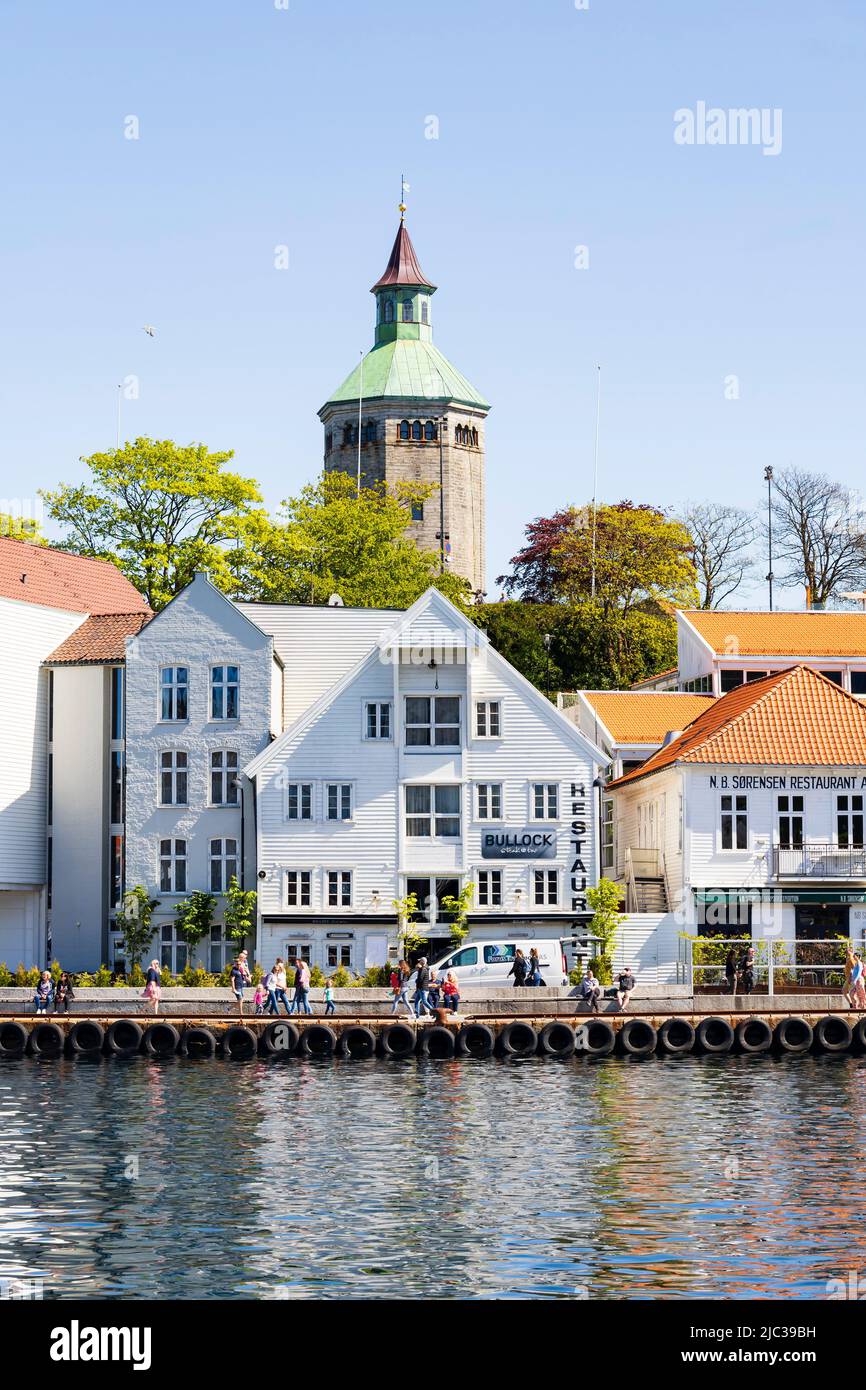 Old quayside warehouses, now restaurants and bars, with the Valberg Tower watchtower behind.Stavanger, Norway Stock Photo