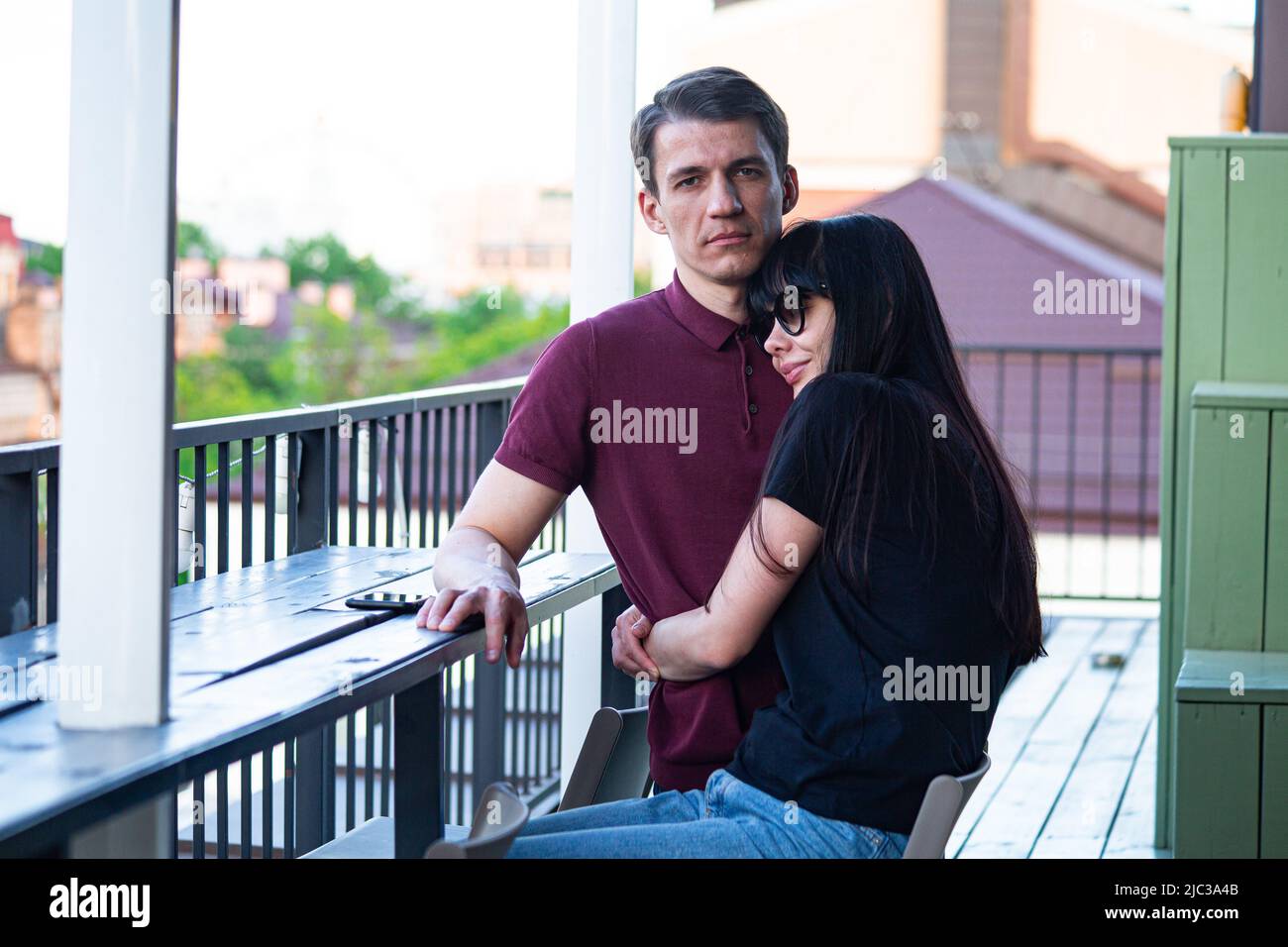 Young pretty woman hugs her man on the roof top in Kiev on Podil (lower city) district, couple enjoys together early June after  turbulent spring 2022 Stock Photo