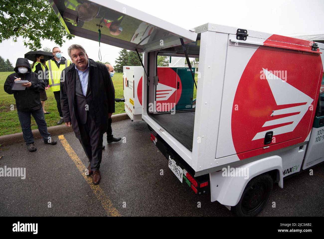 Canada Post CEO Doug Ettinger ducks under the lift gate of a Westward  Max-EV electric delivery vehicle as he checks out its cargo capacity after  a news conference on the postal service‚Äôs
