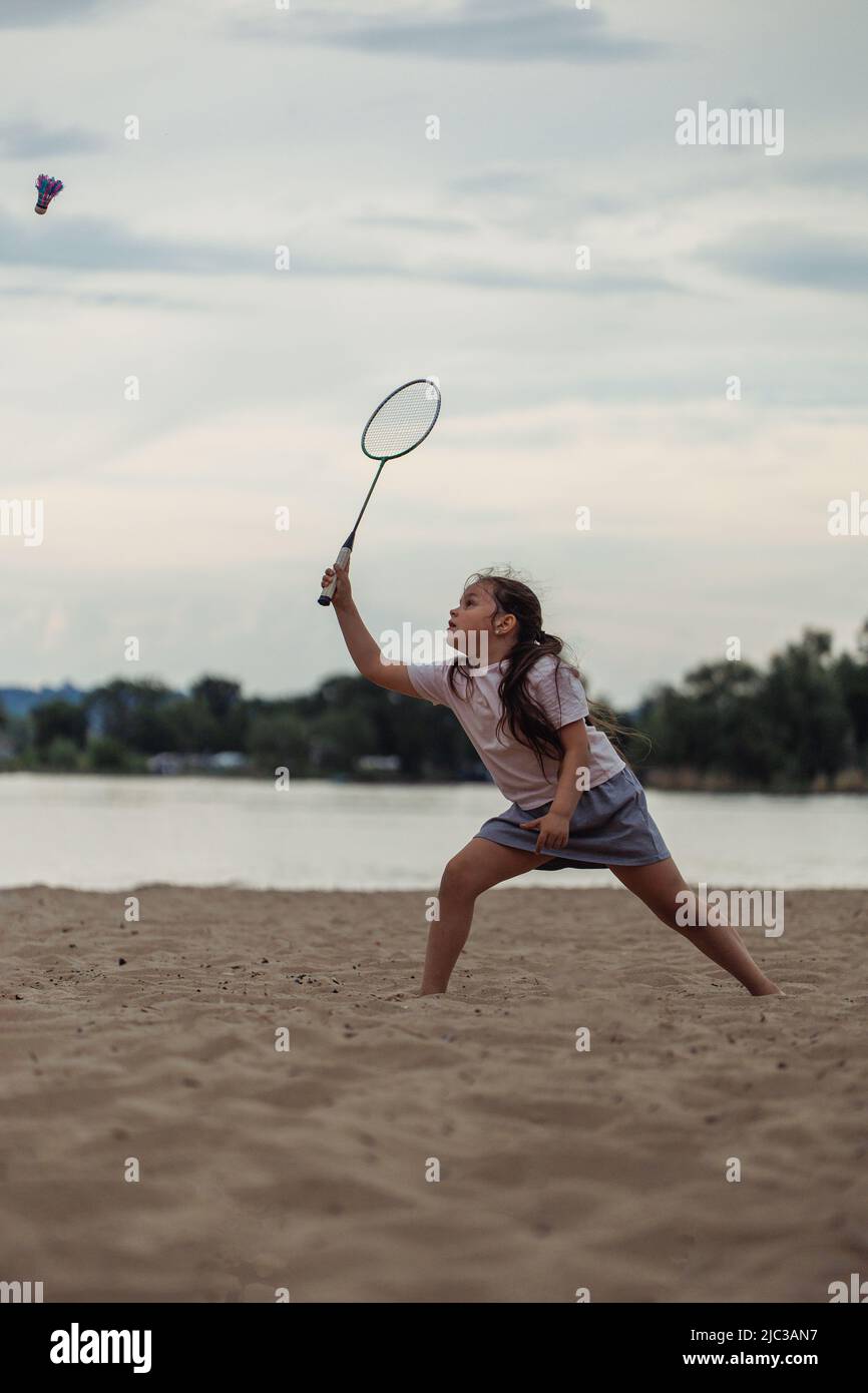 Side view of girl with long dark hair wearing white Tshirt, blue skirt