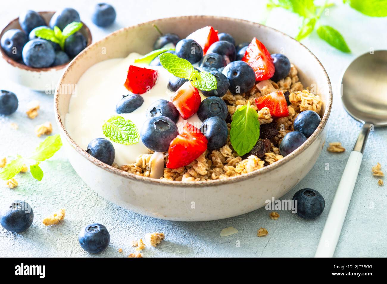 Greek Yogurt with granola and fresh berries at white table Stock Photo