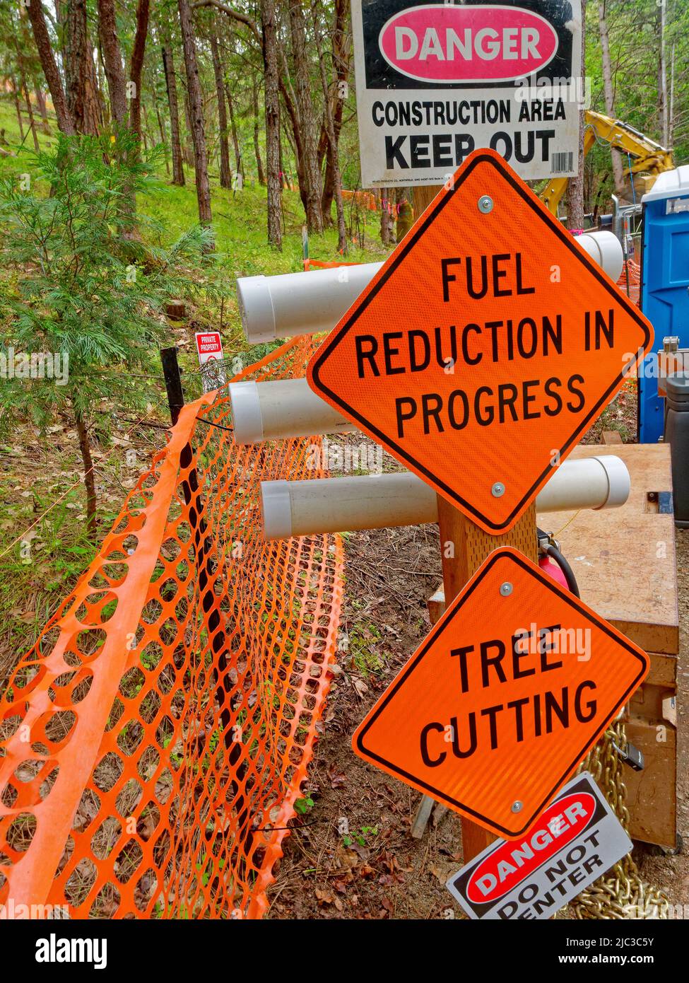 On the hillside above Ashland, Oregon, USA,a sign reads 'fuel reduction in progress' as a crew removes flammable tree lines & shrbs underneath flammable trees. Stock Photo
