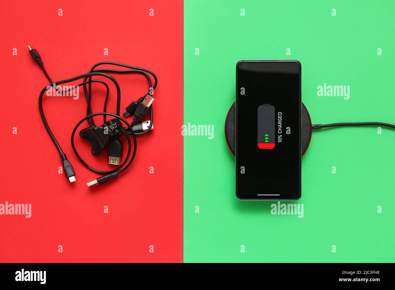 Mobile phone charging on wireless pad and cables on color background