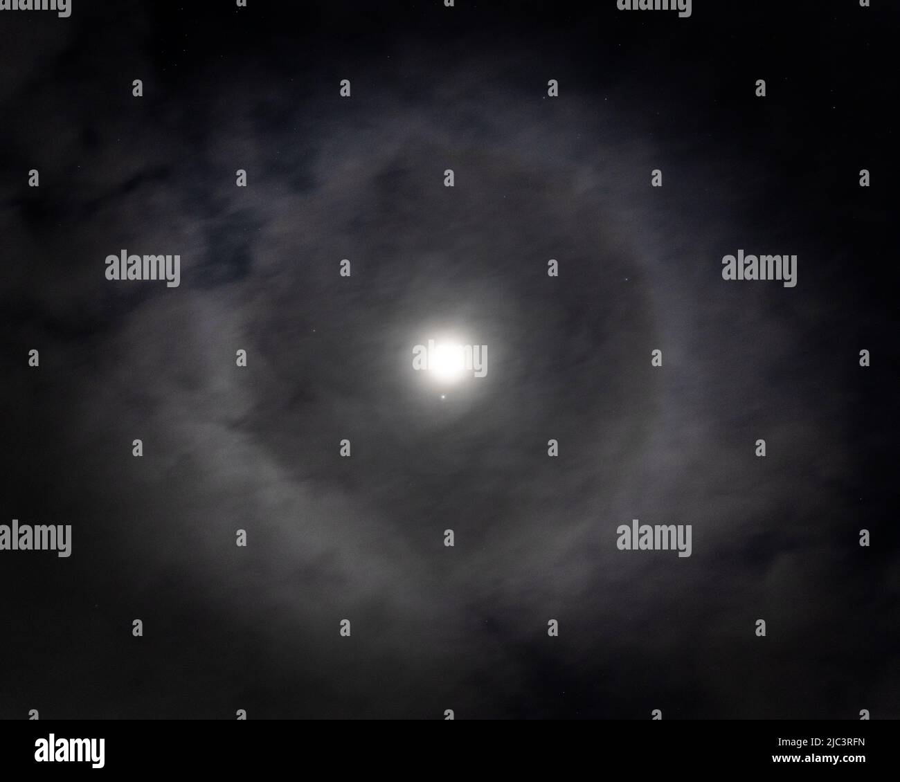 Lunar halo ring around the moon in night time sky with stars Stock Photo
