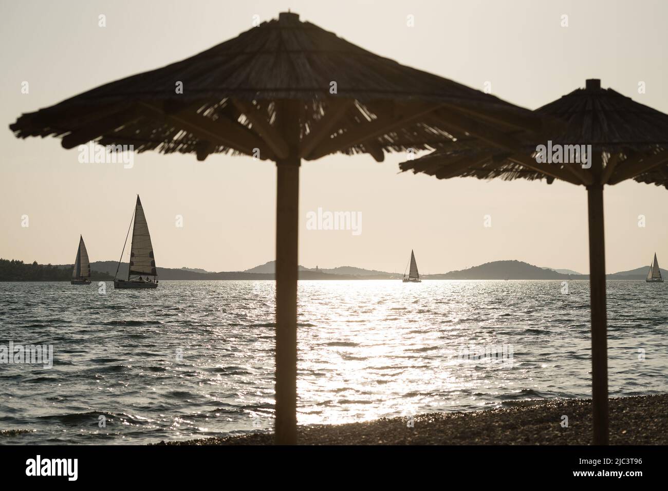 Looking at sailing yachts from beach during sunset Stock Photo