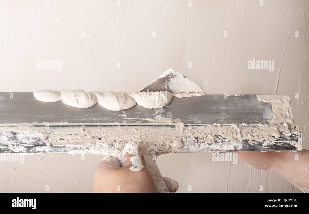 Builder plastering with a spatula and smoothing the wall with plaster. Stock Photo