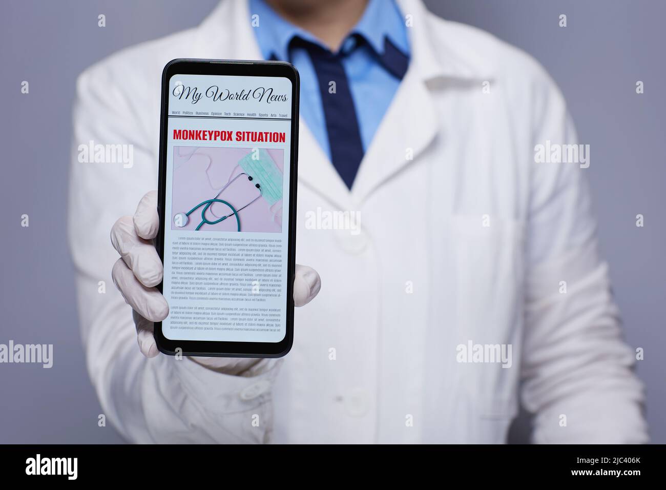 Closeup on modern medical doctor woman in white medical robe showing smartphone with monkeypox news against grey background. Stock Photo