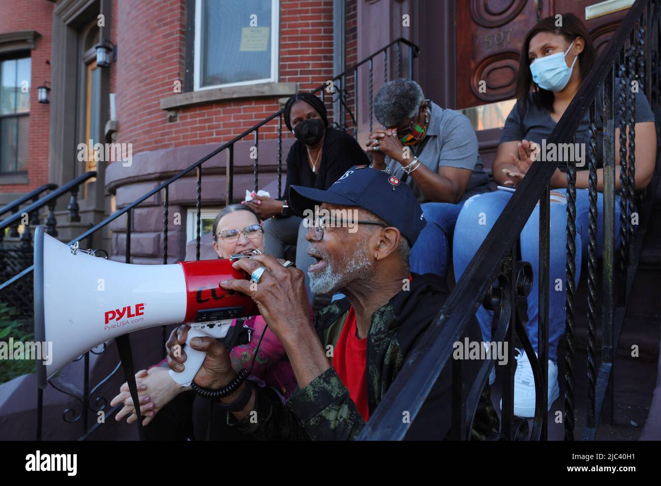 James Harrison, the last tenant in his apartment building, speaks with his family around him from the front stairs to activists holding a vigil to protest Harrison's no-fault eviction so that the owner of the building he has lived in for 30 years can sell it empty, in Boston, Massachusetts, U.S., June 9, 2022.   REUTERS/Brian Snyder Stock Photo