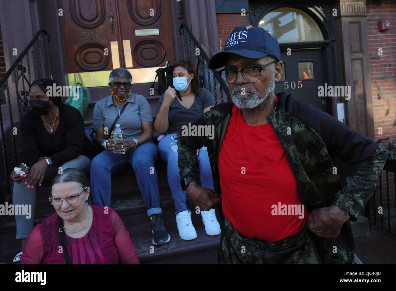 James Harrison, the last tenant in his apartment building, is joined by his family on the front stairs as activists hold a vigil to protest Harrison's no-fault eviction so that the owner of the building he has lived in for 30 years can sell it empty, in Boston, Massachusetts, U.S., June 9, 2022.   REUTERS/Brian Snyder Stock Photo