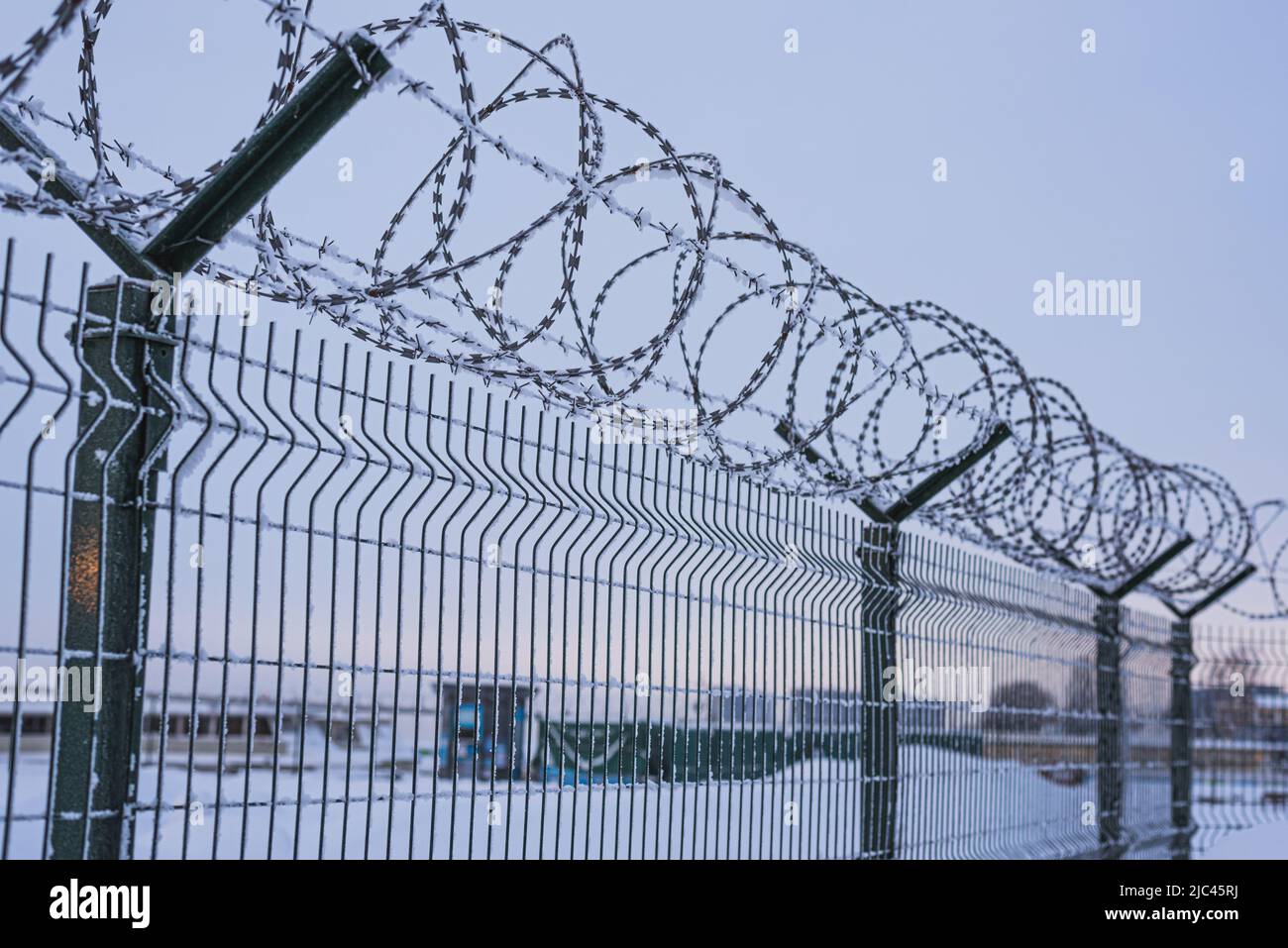 Fence with barbed wire covered with snow in the evening. Stock Photo
