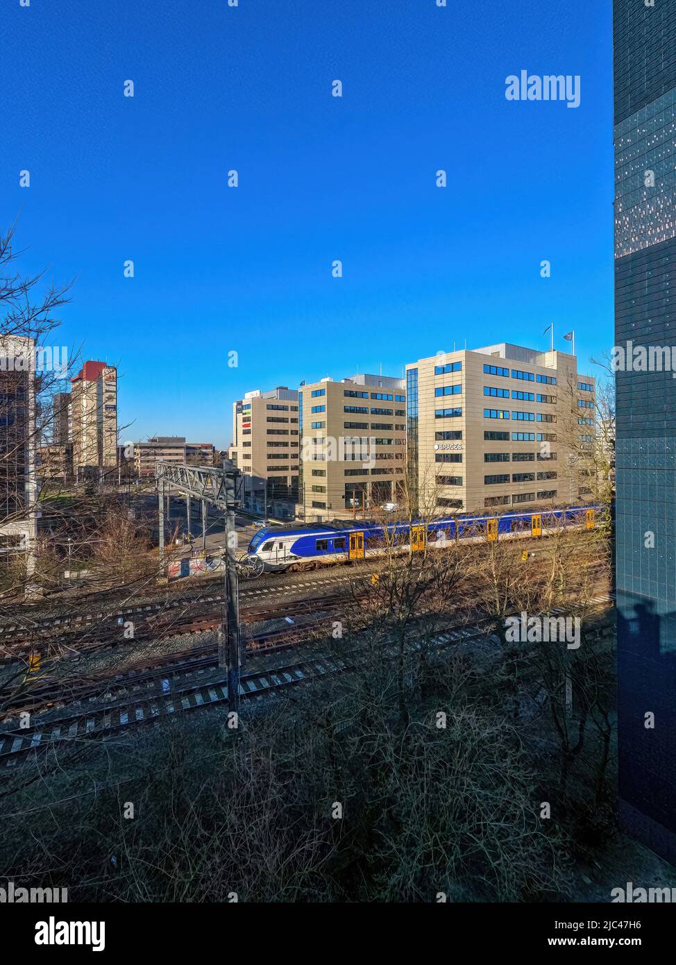Eindhoven, the Netherlands, February 27, 2022: Dutch electrical passenger train leaving Eindhoven Central Station, passing between the office buildings in the city. High quality photo Stock Photo