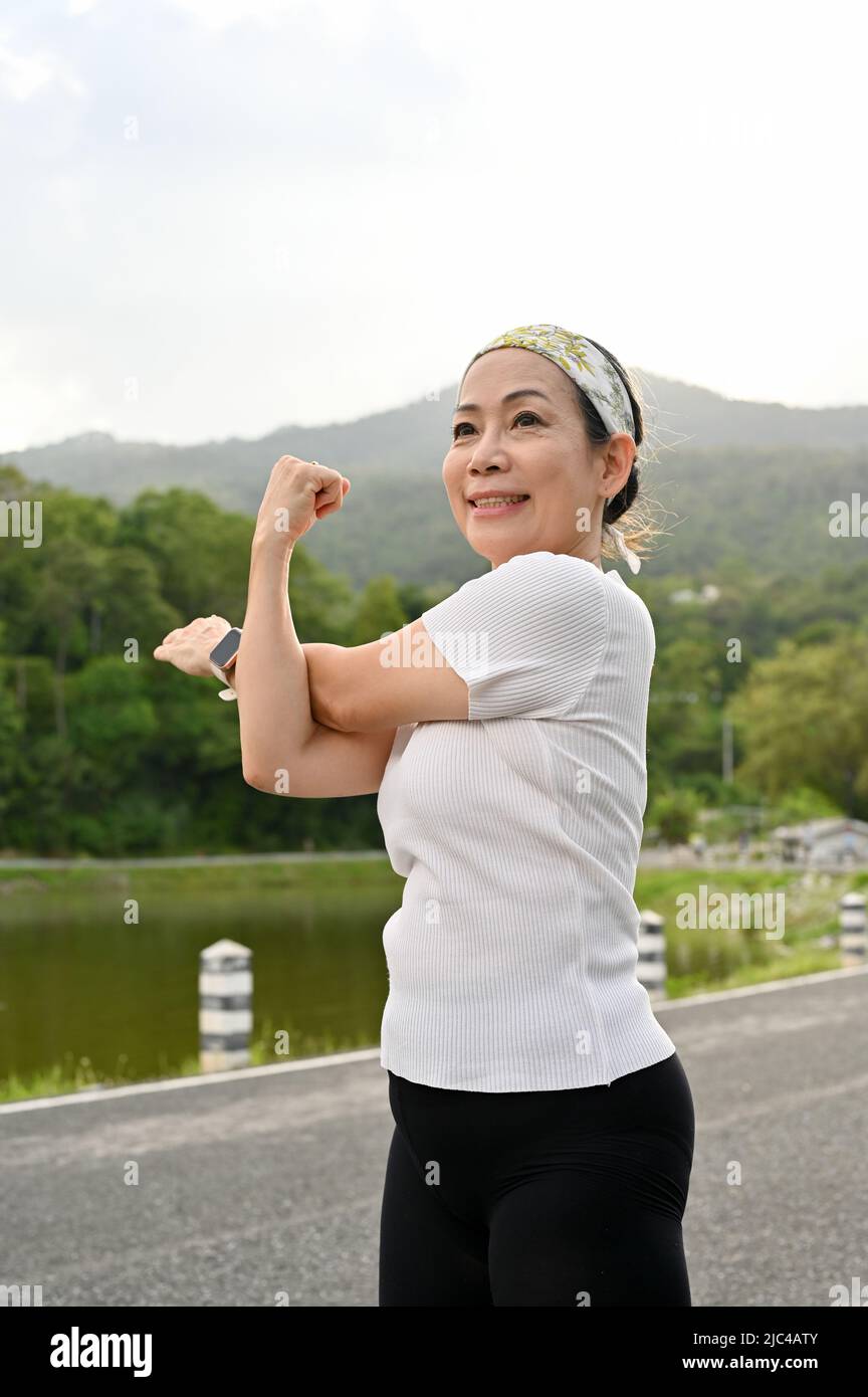 Portrait of a Happy healthy asian aged woman in a sportswear stretching ...
