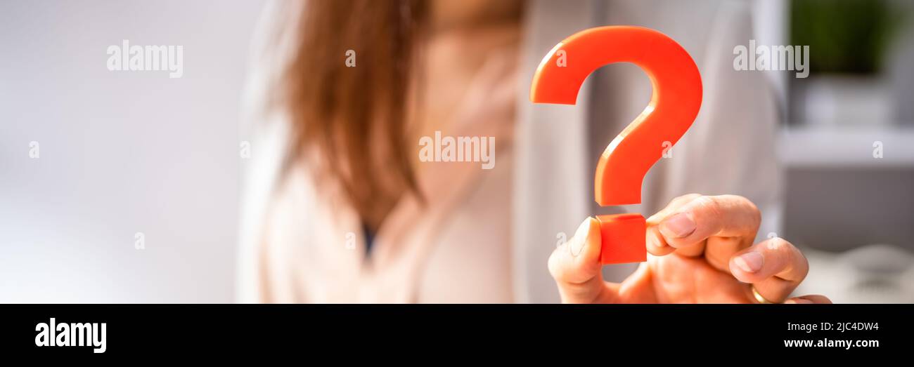 Close-up Of A Businessperson's Hand Holding Red Question Mark Sign Stock Photo