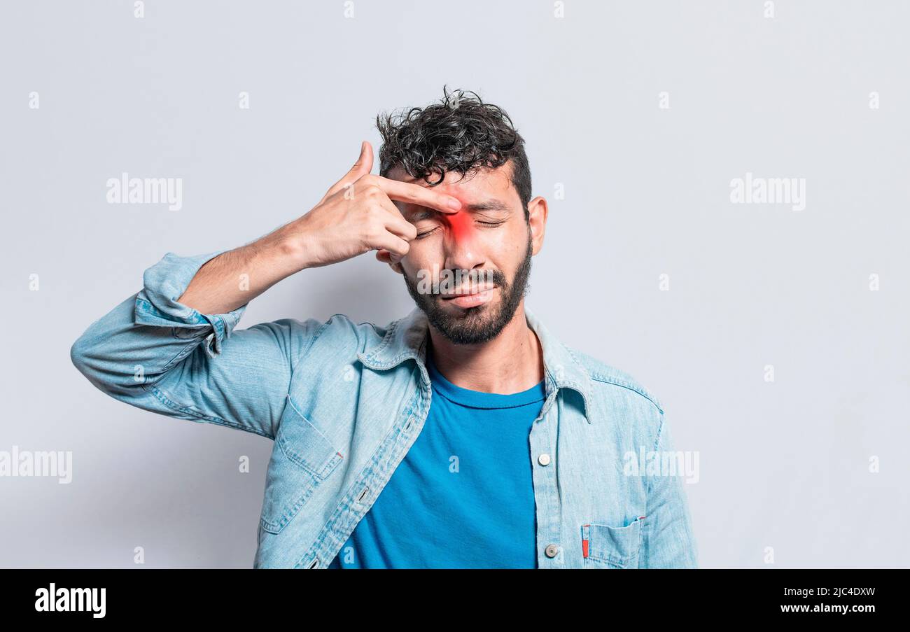 Young man with pain touching nose. A person with nasal bridge pain, Man with nasal bridge headache. Sinus pain concept Stock Photo